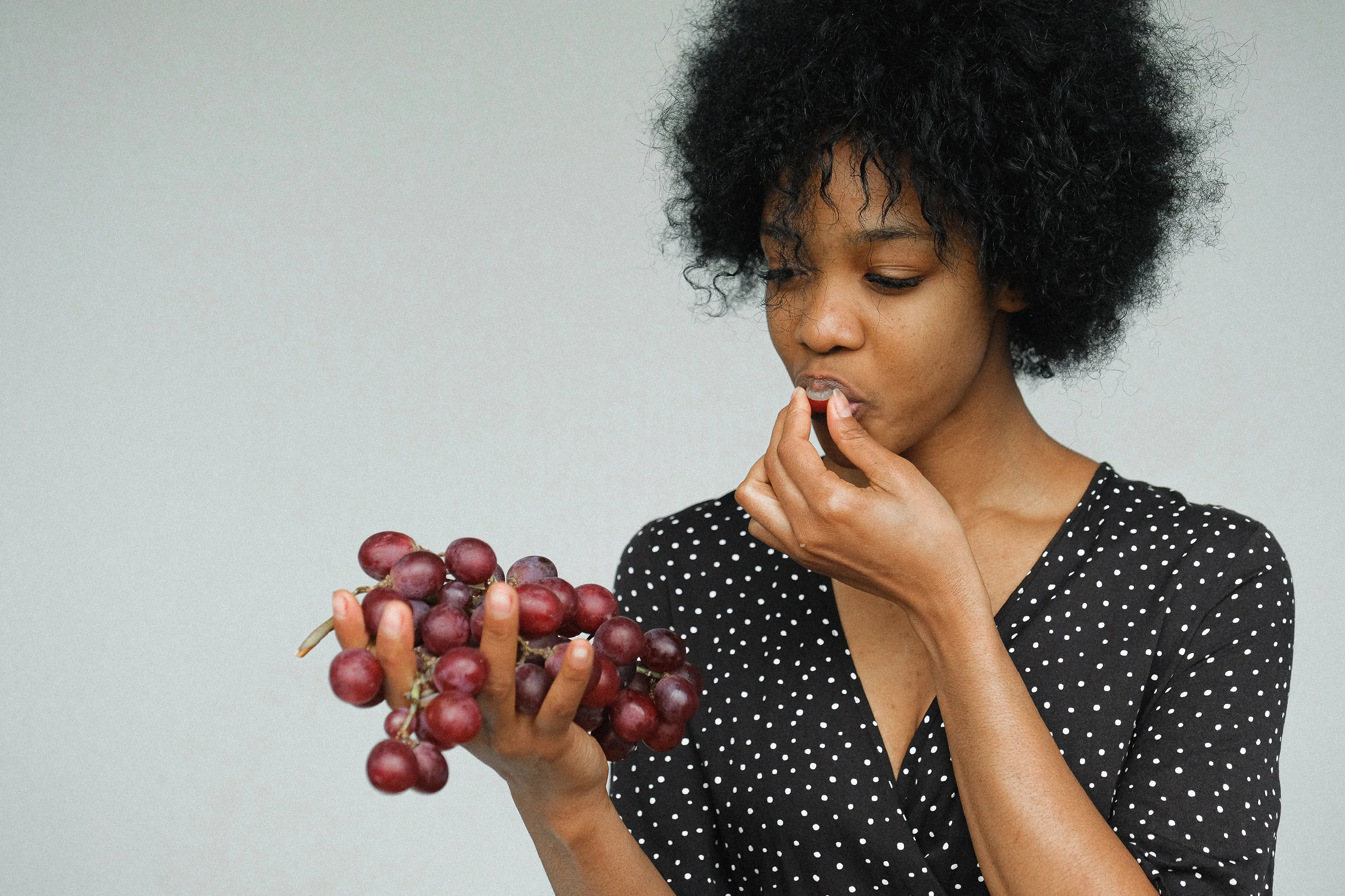 a woman eating a handful of grapes